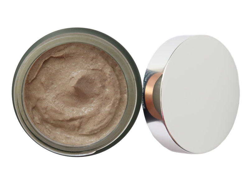 Exfoliating face scrub for removing dead skin cells and helping to clear pores. Presented In a glass jar with silver lid. Open top view.