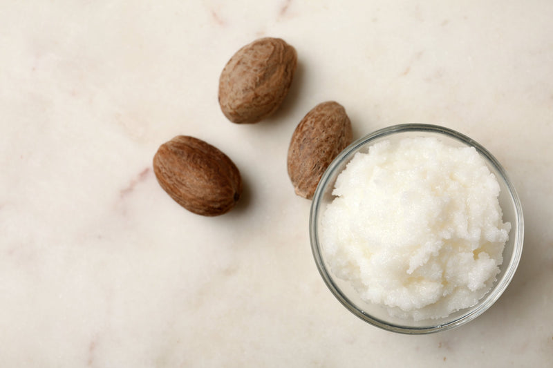 Raw shea butter in bowl and nuts on side 